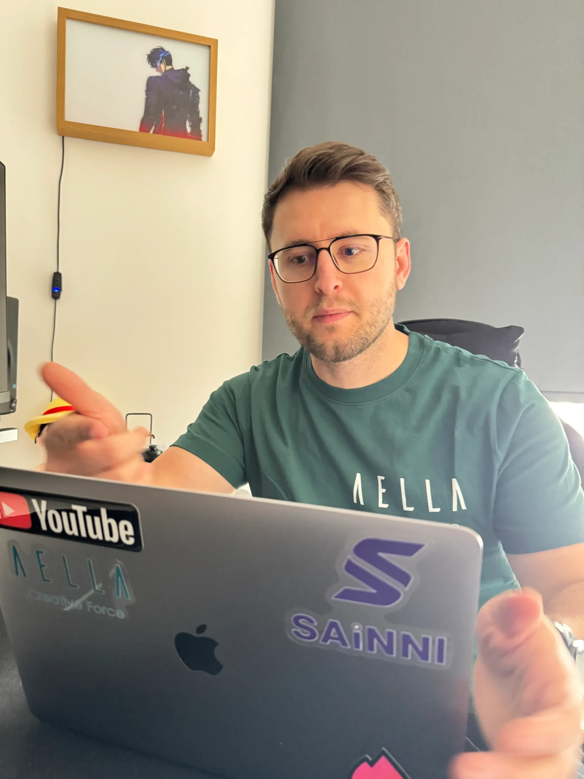 Briken Bufi wearing an Aella Creative Force t-shirt working on a laptop in a modern office.
