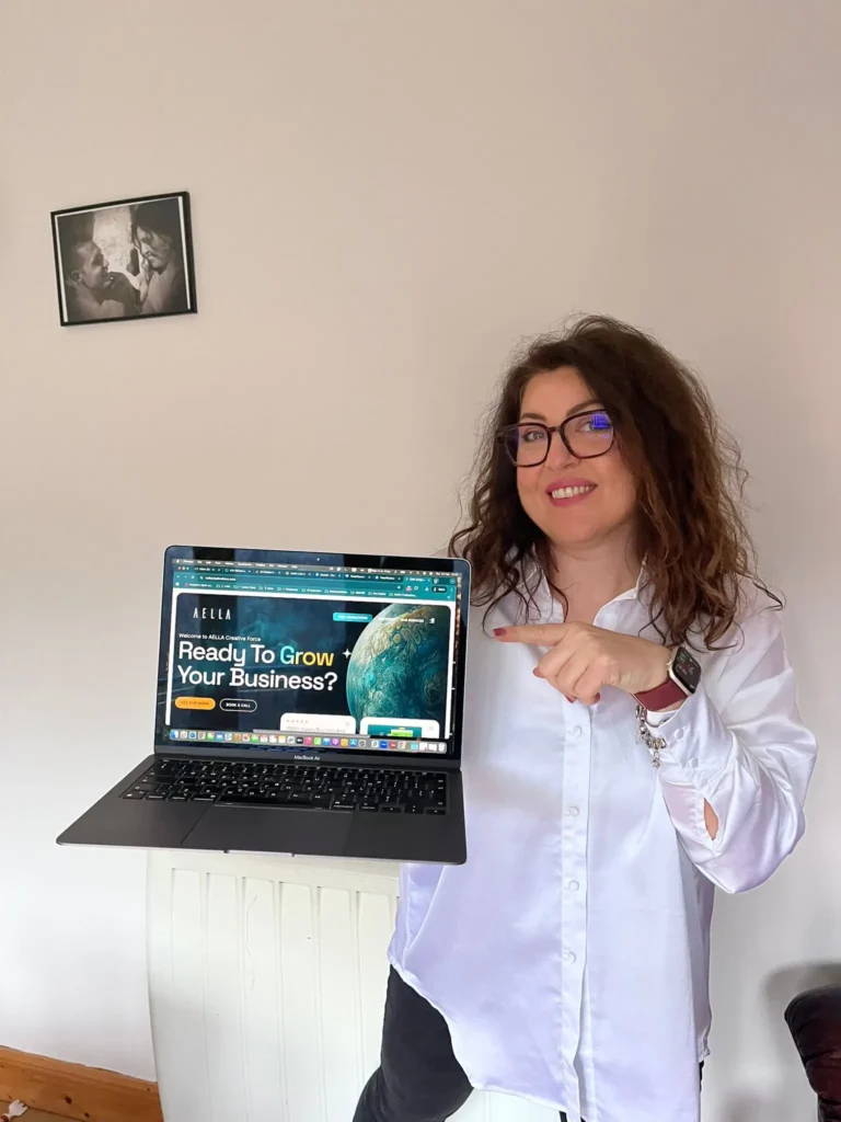 Woman holding a laptop showing the Aella Creative Force website homepage.