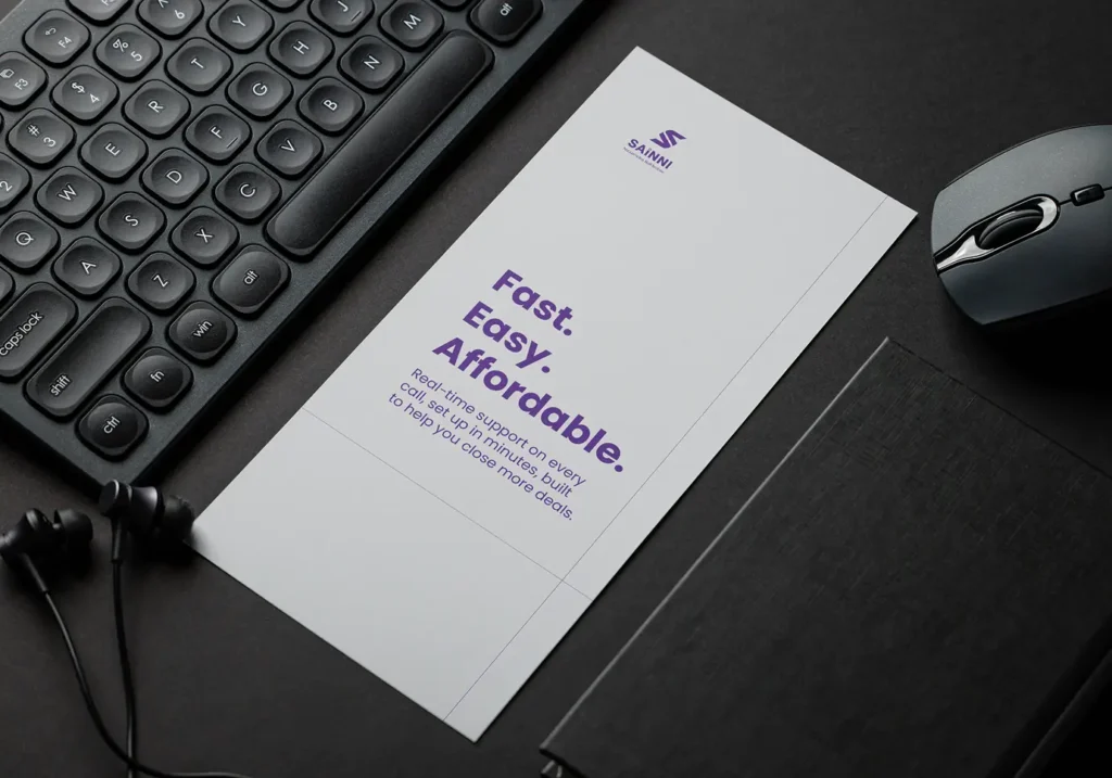 Sainni branded flyer on a dark desk next to a keyboard, mouse and earphones, displaying the words Fast, Easy, Affordable in bold purple typography